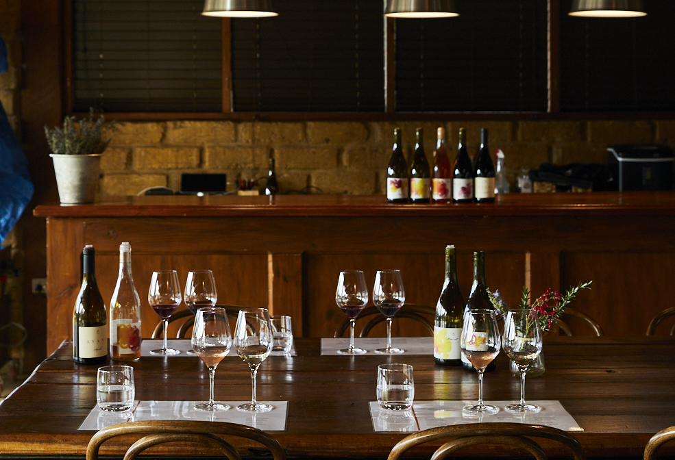 Selection of wines and wine glasses decorate a wooden dining table.