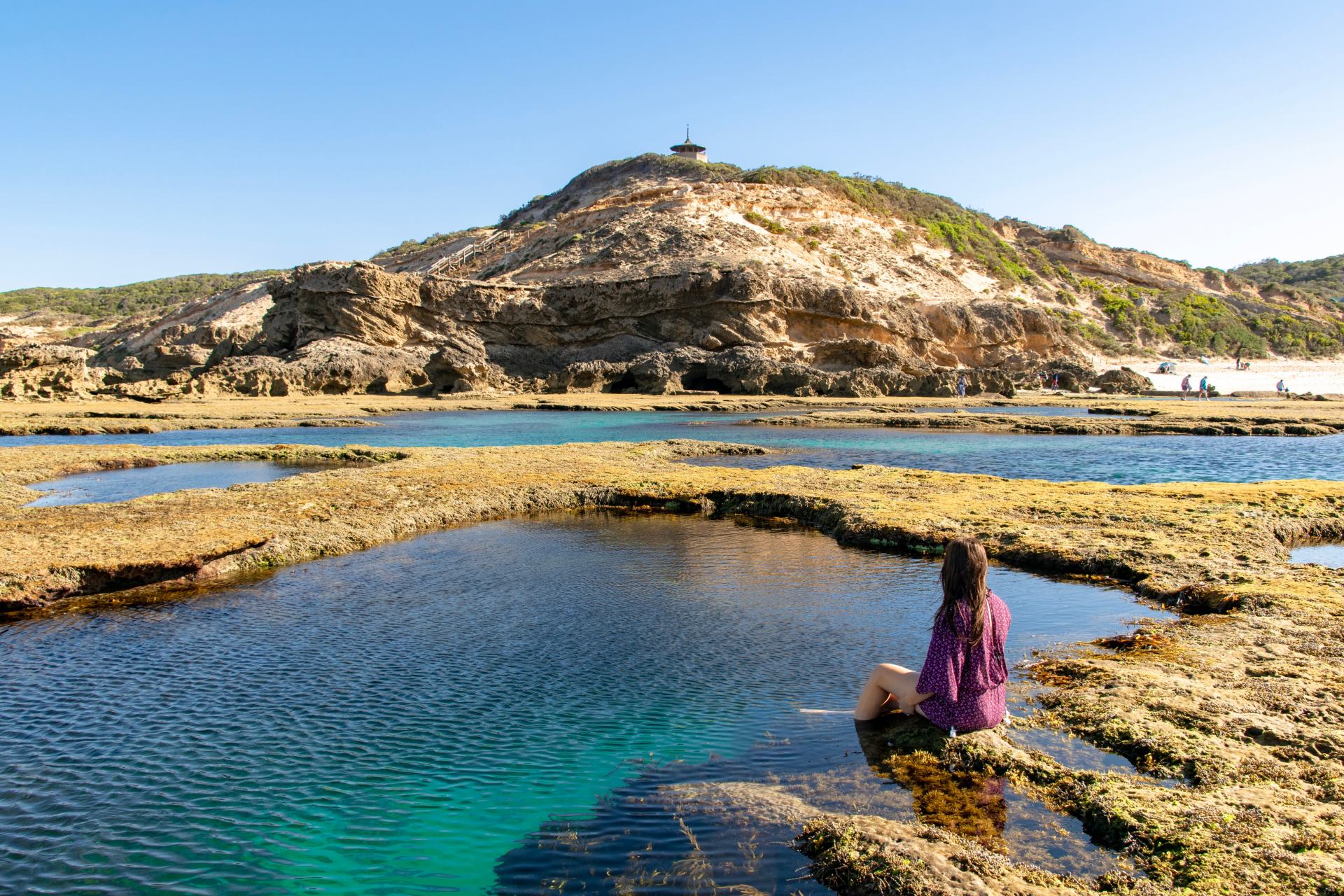 A woman sits amongst the rockpools at Sorrento Back Beach.