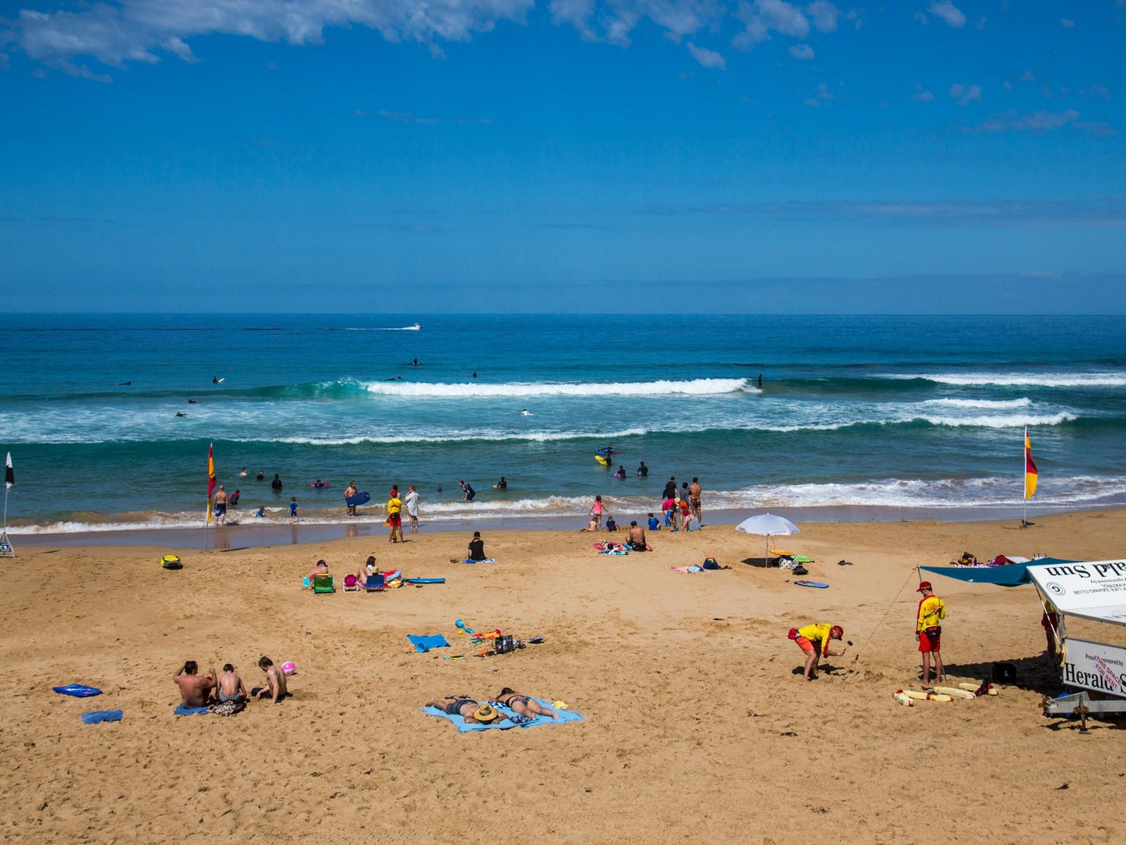Lifesavers, families and wide ranges of people lounge and swim on Gunnamatta beach.